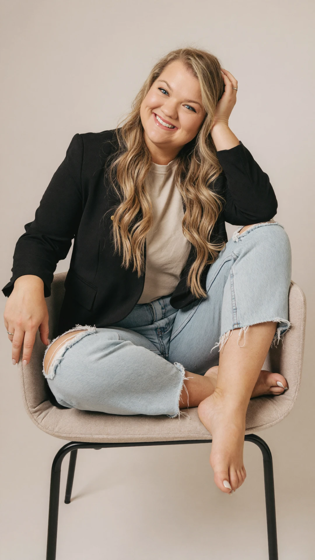 Kendyll smiling, sitting cross-legged in a chair